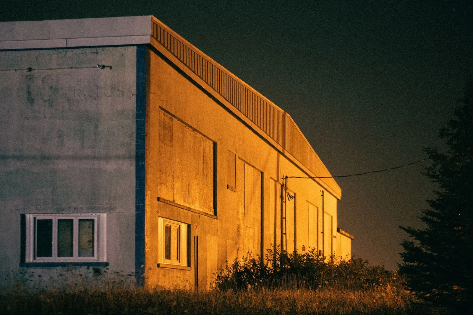 Surveillance d’entrepôts et de sites logistiques Bâtiment industriel éclairé à la tombée de la nuit.